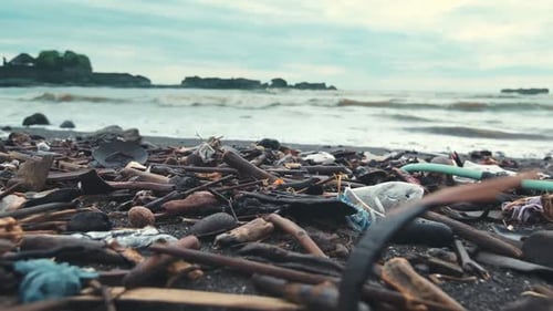 Beach Polluted with Household Garbage and Nondegradable Waste with Tidal Waves