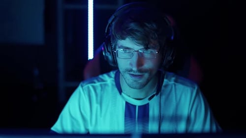 Young Adult Man with Headset Sits in Dark Room
