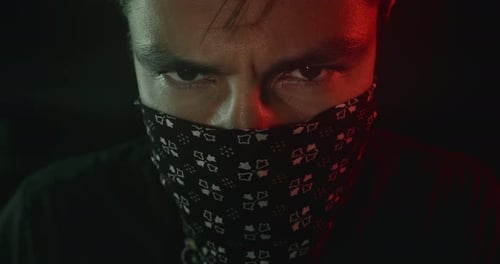 Intense Eyes of Masked Young Man in Shadows