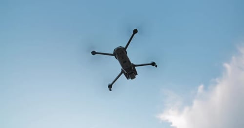 Drone Flies Against Bright Blue Sky. Modern Technologies for Shooting Photos and Videos From Above