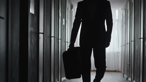 Silhouette of Suited Person Walking Down Hallway