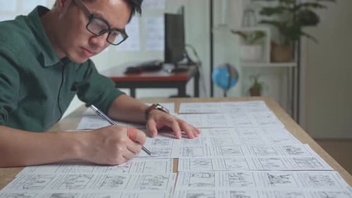 Asian Man Drawing Storyboard Animation Comic Cartoon, Design Creative Scene Layout At Studio