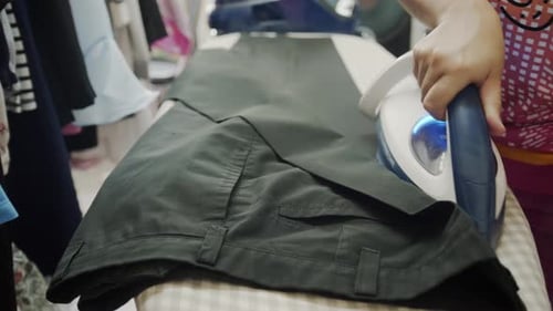 Closeup of a woman ironing clothing by stream iron on board at home
