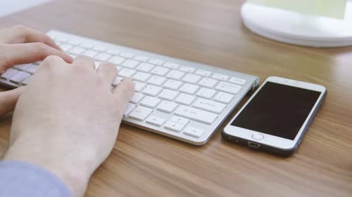 Top View of a Young Man Working with Mobile Phone Computer Keyboard and Mouse