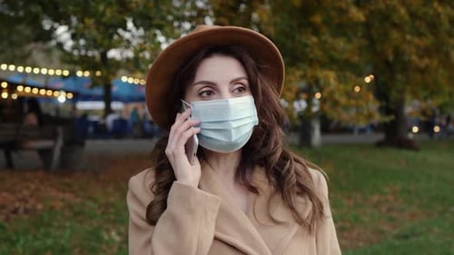 Woman Wearing Face Mask Talking on Phone in Park