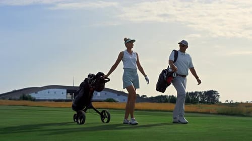 Two Golfers Walk Fairway at Sunset