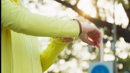 Nahaufnahme einer athletischen Frau, die die Herzfrequenz auf einer Smartwatch misst, während sie sich nach dem Laufen ausruht.