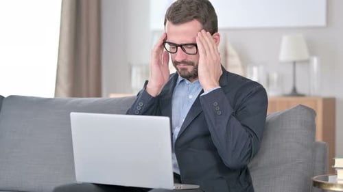 Man Working on Laptop at Home Massages Temples