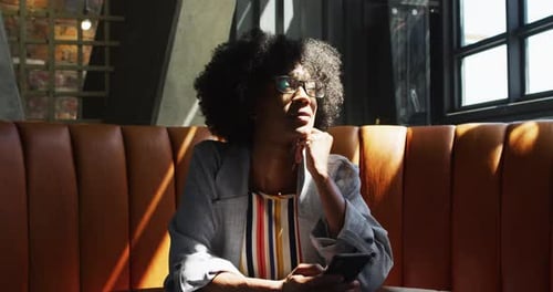African american woman sitting in cafe looking at window and smiling