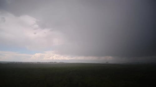 Storm Clouds Over Forest and Distant Buildings