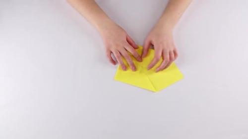 Hands Folding Yellow Paper to Create Origami