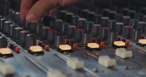 Sound engineer working in a recording studio with a sound console and microphones