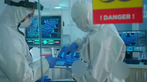 Chemists in Coverall Trying to Develop Vaccine Using Tablet Standing Behind the Glass Wall