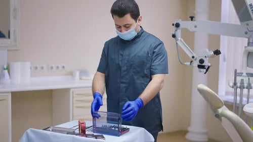 Männlicher Zahnarzt aus dem Nahen Osten öffnet zahnärztliches Chirurgie-Set in Zeitlupe im Büro