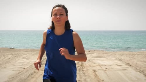 Woman Running on Sandy Beach on Sunny Day