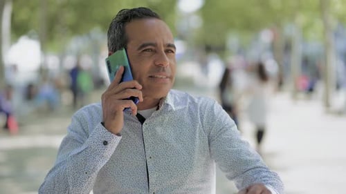 Man Talking By Cell Phone and Walking on Street
