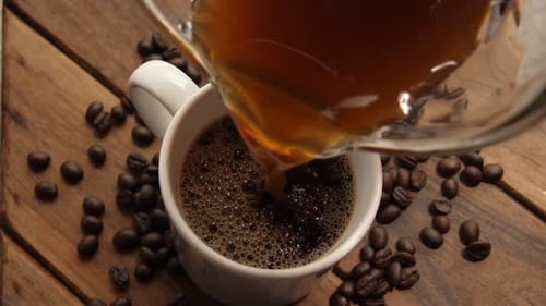 Pouring Hot Coffee Into Mug With Coffee Beans