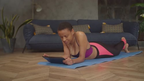 Woman Relaxes with Tablet on Exercise Mat