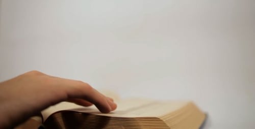 Hand Turns Pages of a Large Book