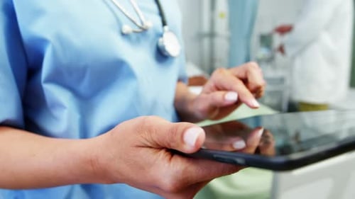 Mid section of female doctor using digital tablet