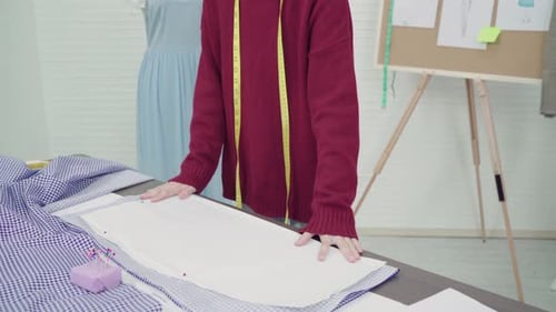 Asian female designer working with fabric sketches and drawing clothing design at the studio.