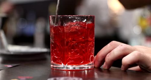 Bartender Stirring a Vibrant Red Cocktail Drink
