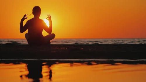 Young Woman Meditates in a Picturesque Place at Sunset