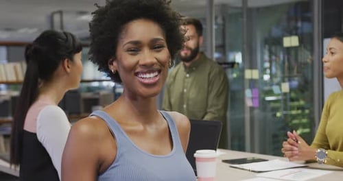 Smiling Woman in Modern Office with Coworkers