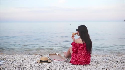 Woman Having a Picnic with Pizza on the Beach