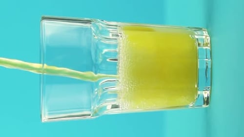 Vertical Video Slow Motion Closeup Shot of Fruit Fizzy Orange Soda Cold Beverage Drink Pooring Into