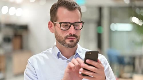 Man Using Smartphone in Bright Office Setting