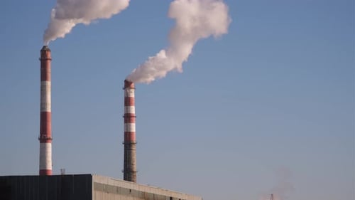 Industrial Chimneys Releasing Smoke Against Clear Sky