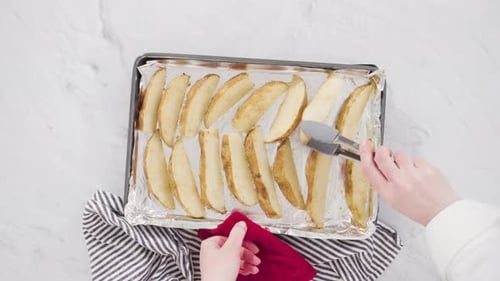 Time lapse. Flat lay. Step by step. Preparing russet potatoes in wedges with olive oil and spices to