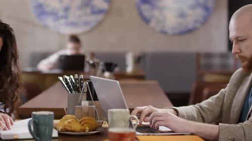 People Working on Laptops in Cafe with Croissants
