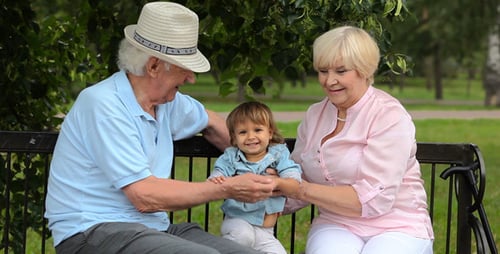 Grandparents and Child Sitting Together on Park Bench