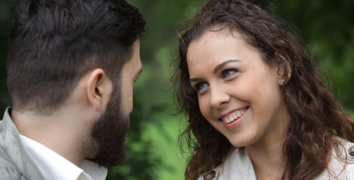 Young Couple Talking and Smiling in a Green Park