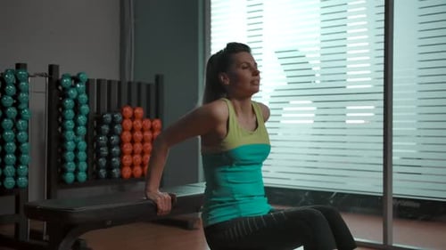 Attraktive Frau im Fitnessstudio macht Trizepsübungen Beugt ihre Arme auf der Bank