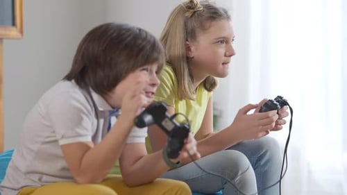 Seitenansicht Porträt konzentrierter fröhlicher kaukasischer Kinder, die zu Hause Spielkonsole spielen