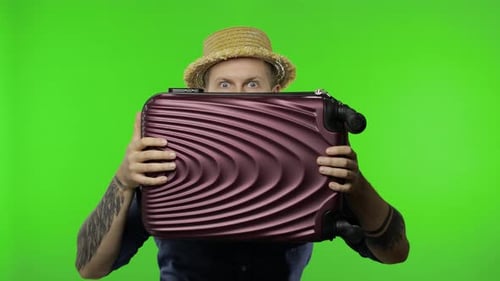 Portrait of Man Tourist Hides Behind a Suitcase and Looks Out. Chroma Key
