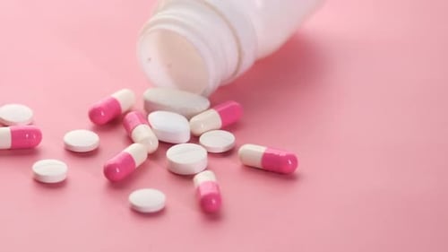 Close Up of Colorful Pills Spilling on Pink Background