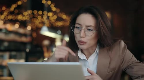 Angry Business Woman Sitting at Cafe Table and Having Serious Conversation Via Video Call
