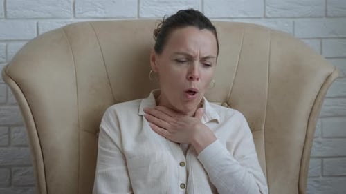 Sick Woman Coughing in Chair at Home
