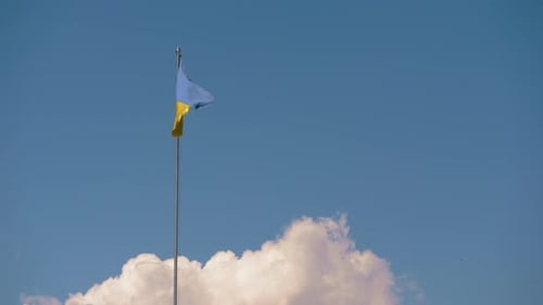 Flag Waving Against Bright Blue Sky With Clouds