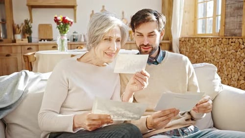 Gray Haired Woman and Man View Old Photographs