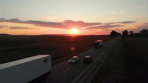 Aerial shot: flying along road with driving vehicles, trucks and cars.