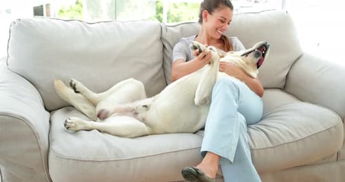 Woman Laughing and Cuddling with Dog on Couch