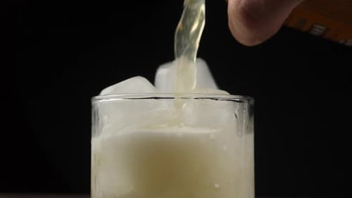 Pouring Drink into Glass with Ice Cubes