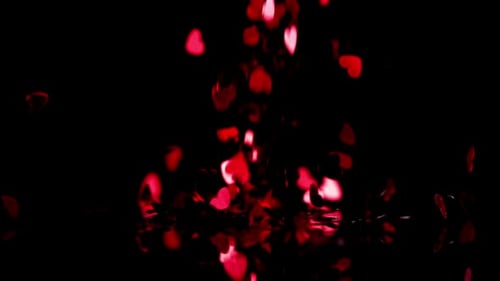 Red heart confetti falling down on black background