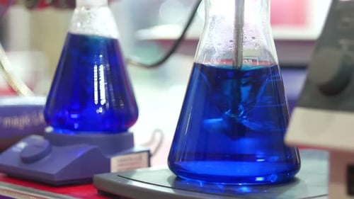 Laboratory Beakers with Blue Liquid Being Mixed