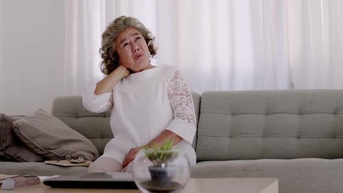 Senior Woman Massaging Stiff Neck at Home